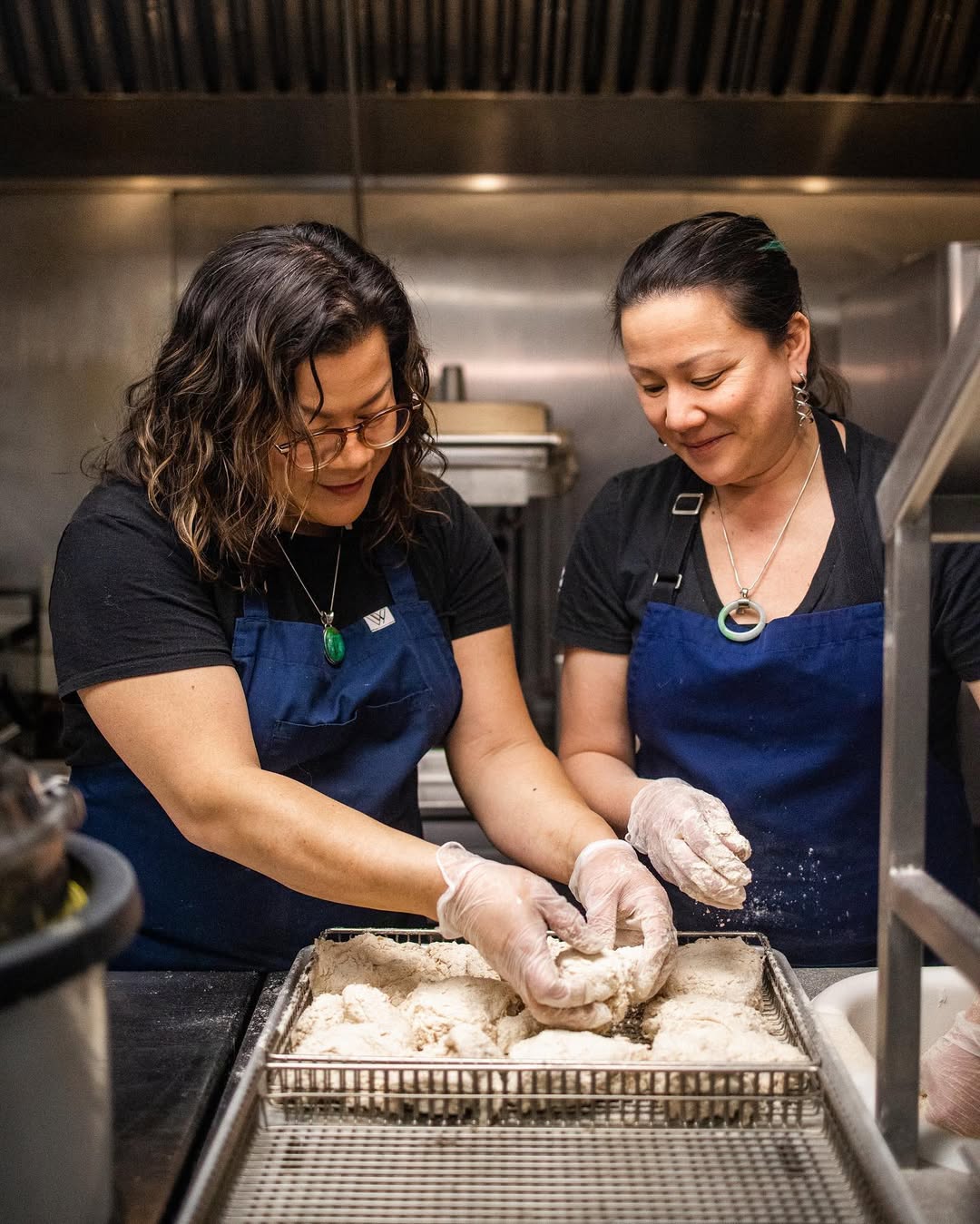 Nicole and Francine Gomes preparing fried chicken in a commercial kitchen, showcasing their chef expertise and commitment to quality at Cluck N Cleaver.